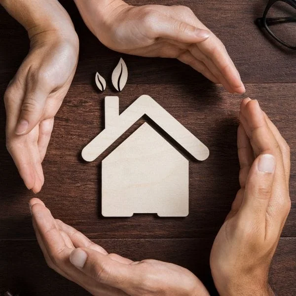 Manos protegiendo una vivienda ecológica como símbolo de seguro de hogar en La Rioja